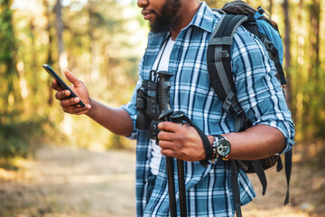 Young man enjoys hiking and using mobile phone in nature.	