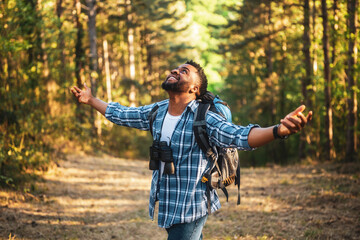 Happy young man hiker with arms raised enjoys in the nature.	
