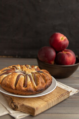 homemade peach pie on a wooden board on a black background