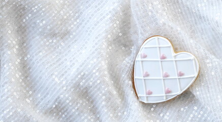White Gingerbread Heart on a Light Background with Sequins. A Magical Holiday Atmosphere. The...
