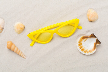 Stylish sunglasses on sand background, top view