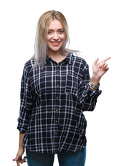 Young blonde woman over isolated background with a big smile on face, pointing with hand and finger to the side looking at the camera.