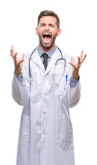 Young handsome doctor man over isolated background crazy and mad shouting and yelling with aggressive expression and arms raised. Frustration concept.