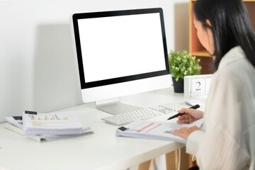 Side view of female accountant sitting at her workplace in front of blank computer monitor