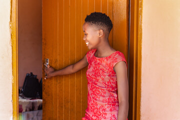black teenager going to school village township in south africa, entering the room to pick her...