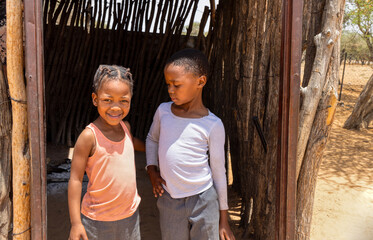 two village african girls with braids standing at the entrance of the shack, township village in...