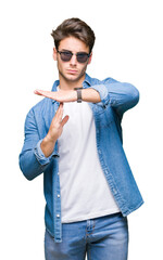 Young handsome man wearing sunglasses over isolated background Doing time out gesture with hands,...
