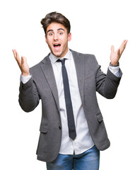 Young business man wearing suit and tie over isolated background celebrating crazy and amazed for success with arms raised and open eyes screaming excited. Winner concept