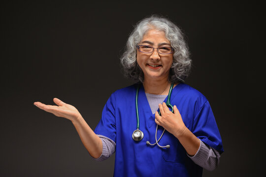 Portrait Of Senior Doctor Coat Presenting And Pointing With Palm Of Hand On Black Background