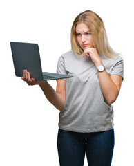 Young caucasian woman using computer laptop over isolated background serious face thinking about...