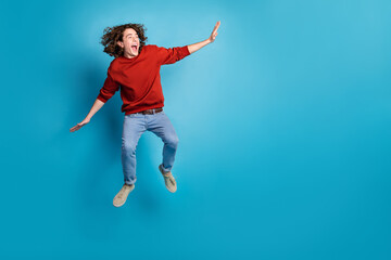 Full length photo of funky cool guy dressed red pullover jumping high flying emtpy space isolated...