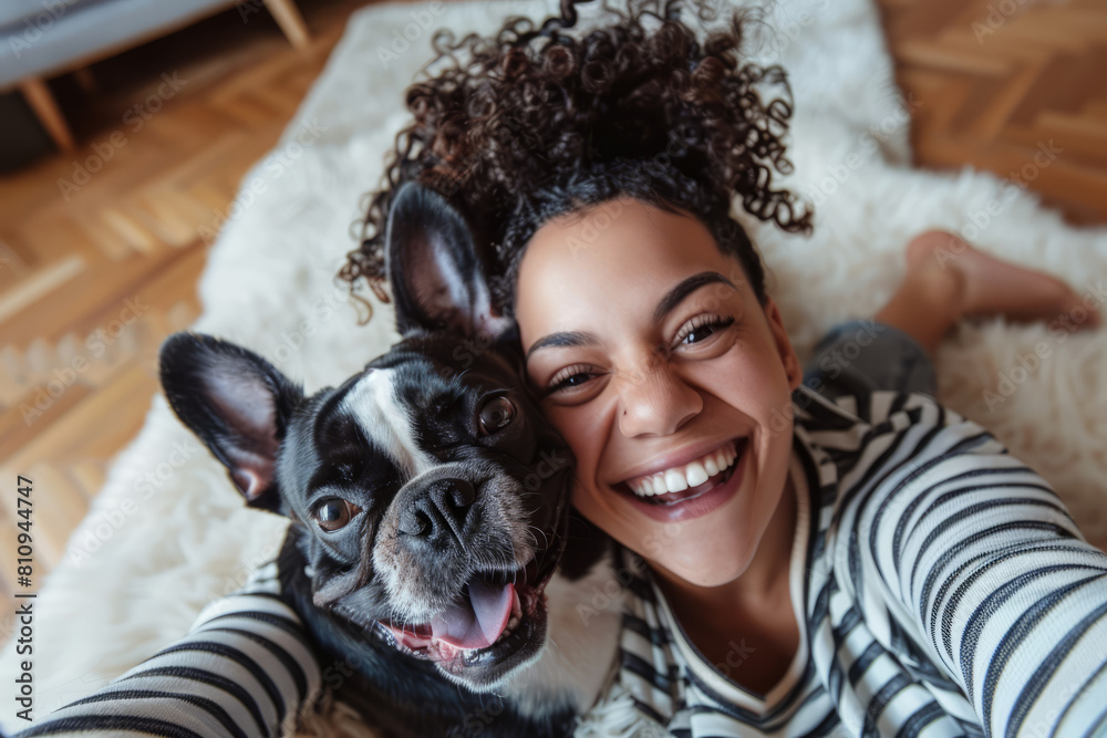 Wall mural a joyful african american woman is taking a selfie with her cheerful pet, who has a funny expression