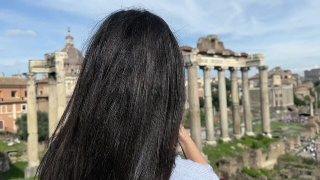 Young attractive raven hair woman taking pictures from Roman Forum on sightseeing tour in Rome, Italy