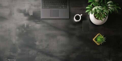 黒いデスクの俯瞰視点、ノートパソコンと観葉植物、スマートフォン

