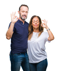 Middle age hispanic casual couple over isolated background relax and smiling with eyes closed doing meditation gesture with fingers. Yoga concept.