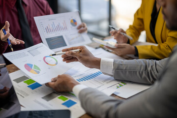 A group of people are looking at graphs and charts on a table. They are discussing the data and making decisions based on the information presented