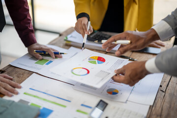 A group of people are looking at a table with graphs and charts. They are discussing the data and making decisions based on the information