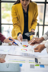 A group of people are gathered around a table with papers and calculators. They are discussing and working on a project