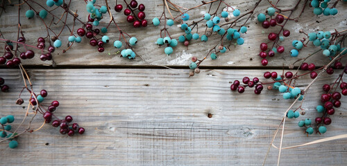 Teal and maroon berries create a graceful Memorial Day scene on a weathered wood backdrop.