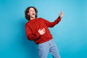 Photo of funky cool guy dressed red pullover playing guitar emtpy space isolated blue color...