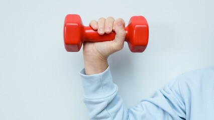 Woman's hand lifting a red dumbbell on a white background