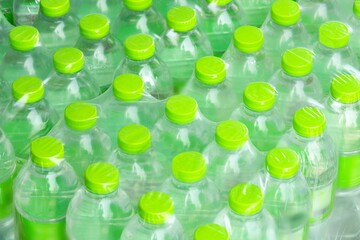 A row of green plastic bottles with green lids. The bottles are lined up in a row and are all the same size