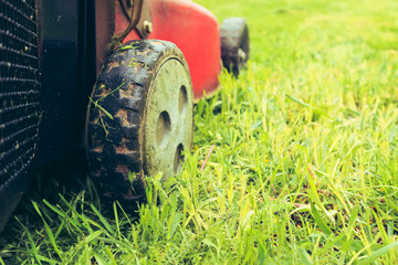 Lawnmover on on a grassy grass. An old red lawn mower mowing lush green grass