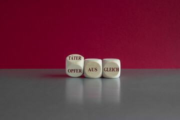 Wooden cubes form the German expression 'Taeter Opfer Ausgleich' (victim-offender compensation). Beautiful grey table pink background. Business concept.