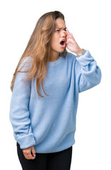 Young beautiful brunette woman wearing blue winter sweater over isolated background shouting and screaming loud to side with hand on mouth. Communication concept.