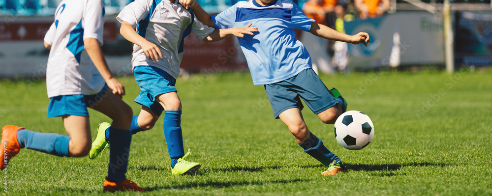 Wall mural Youth soccer football league. Young boys in white and blue soccer jerseys play tournament match during youth football tournament