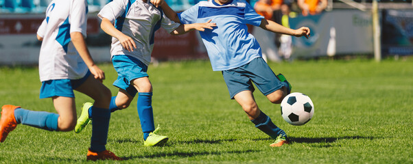 Youth soccer football league. Young boys in white and blue soccer jerseys play tournament match during youth football tournament