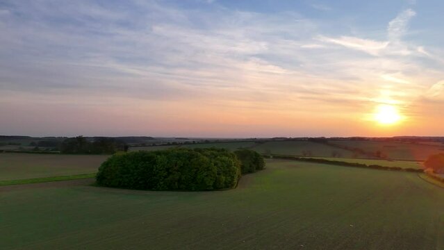 Golden sunset over English farmland in spring. Norfolk landscape drone aerial slow panoramic angle