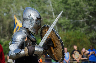 Battle of warriors tournament. Armed member of history club in knight armor demonstrating fighting...