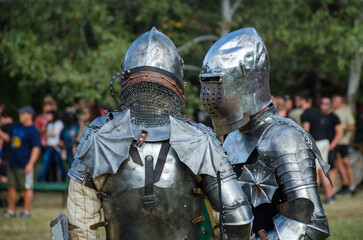 Battle of warriors tournament. Armed members of history club in knight armor demonstrating fighting...