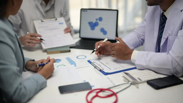 Three people are sitting at a table with a red stethoscope on it. They are discussing something important