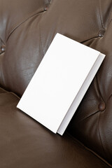 Book with blank cover on leather sofa