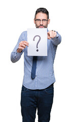 Handsome young business man holding paper with question mark over isolated background pointing with finger to the camera and to you, hand sign, positive and confident gesture from the front