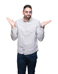 Fototapeta premium Young handsome man wearing sunglasses over isolated background clueless and confused expression with arms and hands raised. Doubt concept.