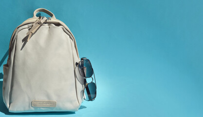 beige backpack for school, travel, bag for things. sunglasses. an element of the wardrobe. background for the design.
