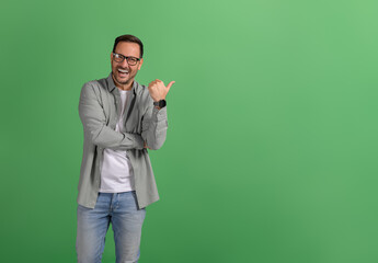 Portrait of ecstatic salesman presenting empty space for marketing on isolated green background