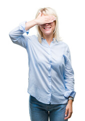 Young beautiful blonde business woman wearing glasses over isolated background smiling and laughing with hand on face covering eyes for surprise. Blind concept.