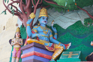 The four-armed God Vishnu sits under a tree next to Garuda. Religious sculpture near a Hindu temple...