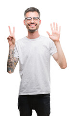 Young tattooed adult man showing and pointing up with fingers number seven while smiling confident and happy.