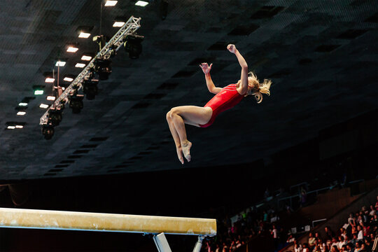 exercise on balance beam gymnastics, female gymnast perform backward somersault landing on floor