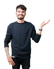 Naklejka premium Young handsome man over isolated background smiling cheerful presenting and pointing with palm of hand looking at the camera.