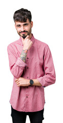 Young handsome man wearing pink shirt over isolated background looking confident at the camera with smile with crossed arms and hand raised on chin. Thinking positive.