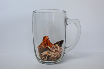 Wedang Uwuh, or Javanese herbal drink, inside transparante glass, isolated on white background. Ingredients before brewed of Indian redwood, dried ginger, lemongrass and cardamom