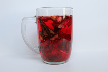 Wedang Uwuh, or traditional tea from brewed sappanwood, ginger, lemongrass and cardamom. In transparent glass, isolated on white background