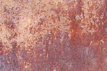 A very old rusty metal surface with peeling paint.
