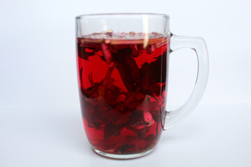 Wedang Uwuh, or traditional tea from brewed sappanwood, ginger, lemongrass and cardamom. In transparent glass, isolated on white background